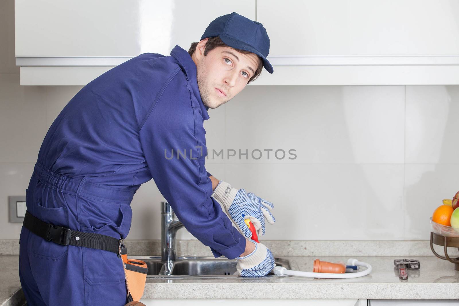 Serious plumber fixing the sink