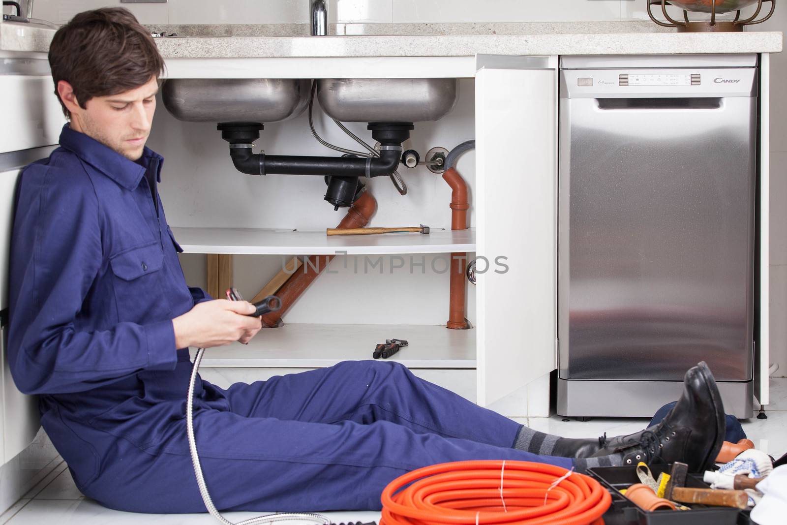 Plumber fixing the pipe sitting on the floor