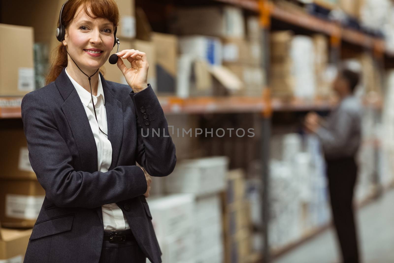 Elegant manager talking into a headset in a large warehouse