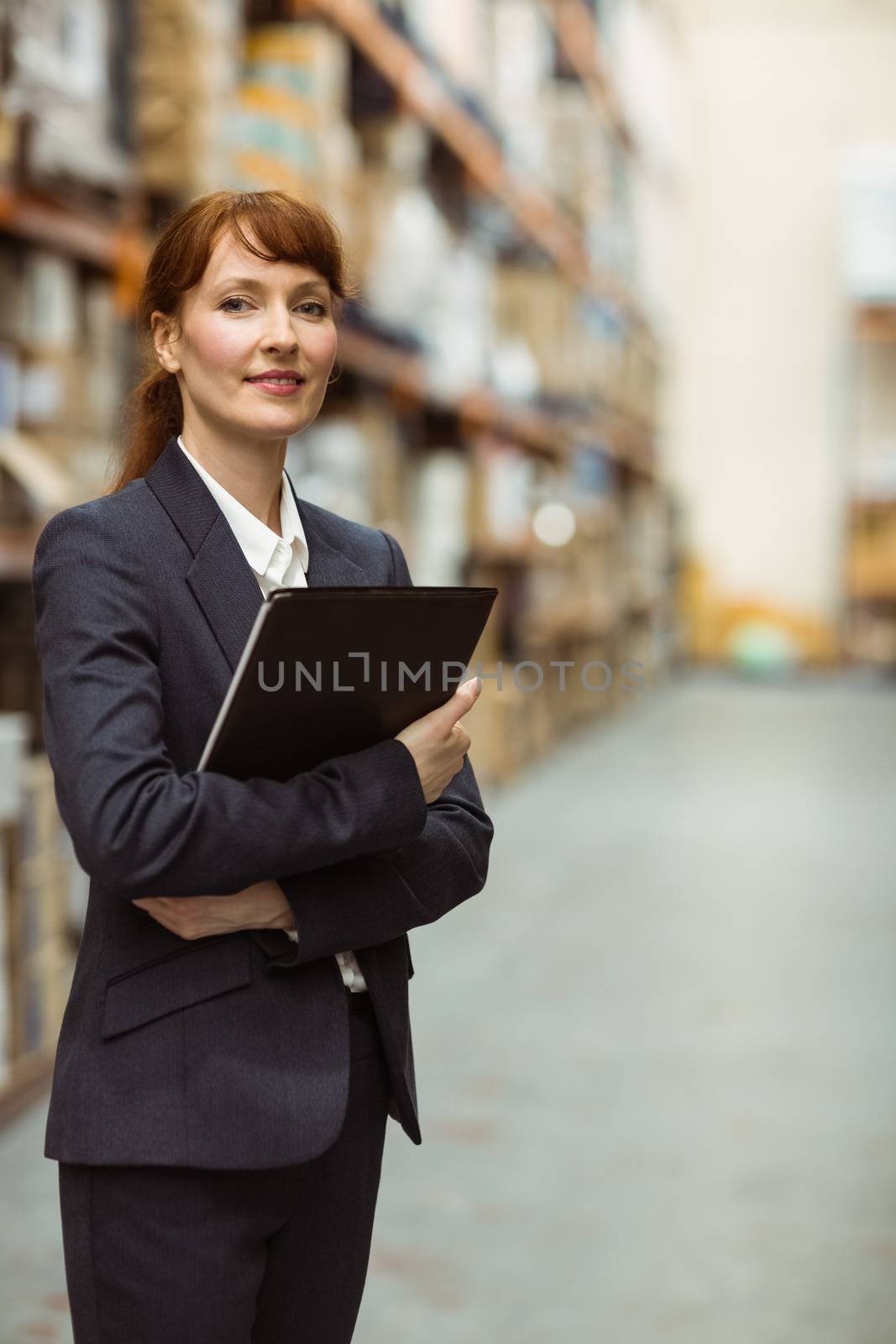 Portrait of pretty manager holding folder in a large warehouse