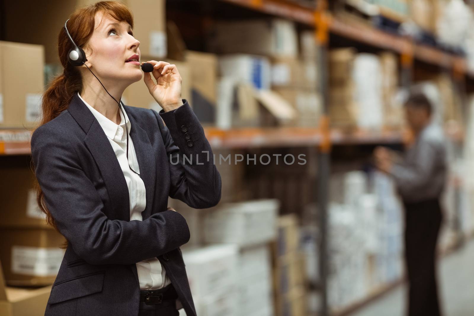 Elegant manager talking into a headset in a large warehouse