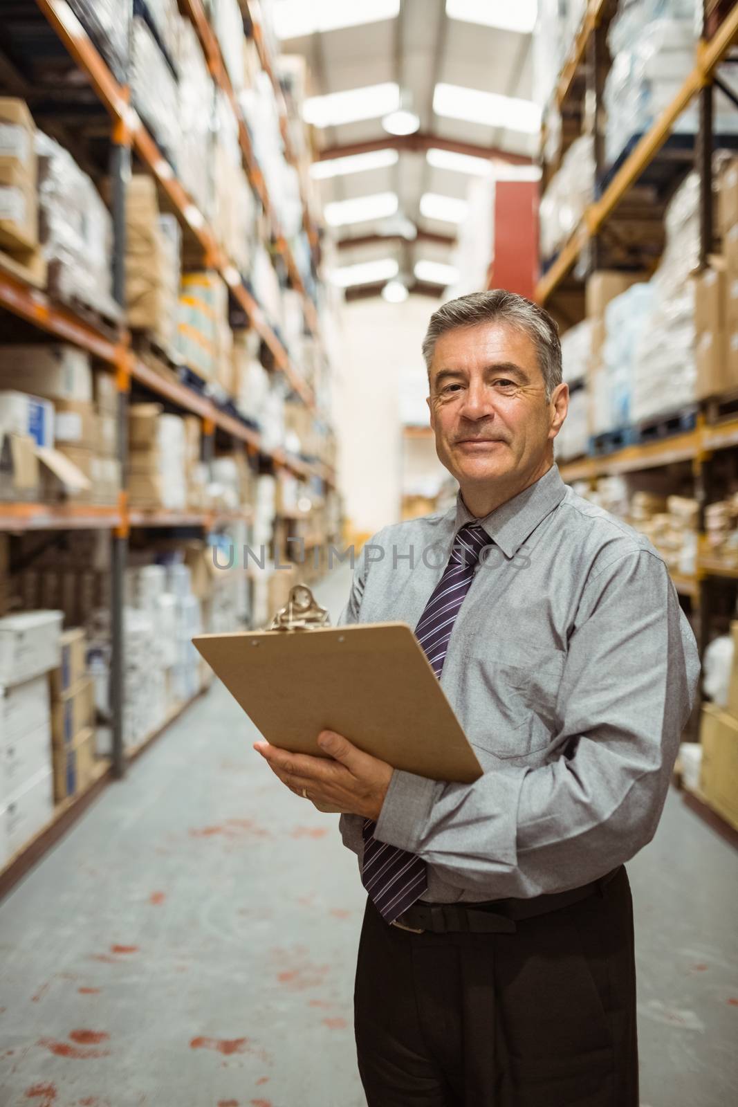 Smiling warehouse manager holding a clipboard by Wavebreakmedia