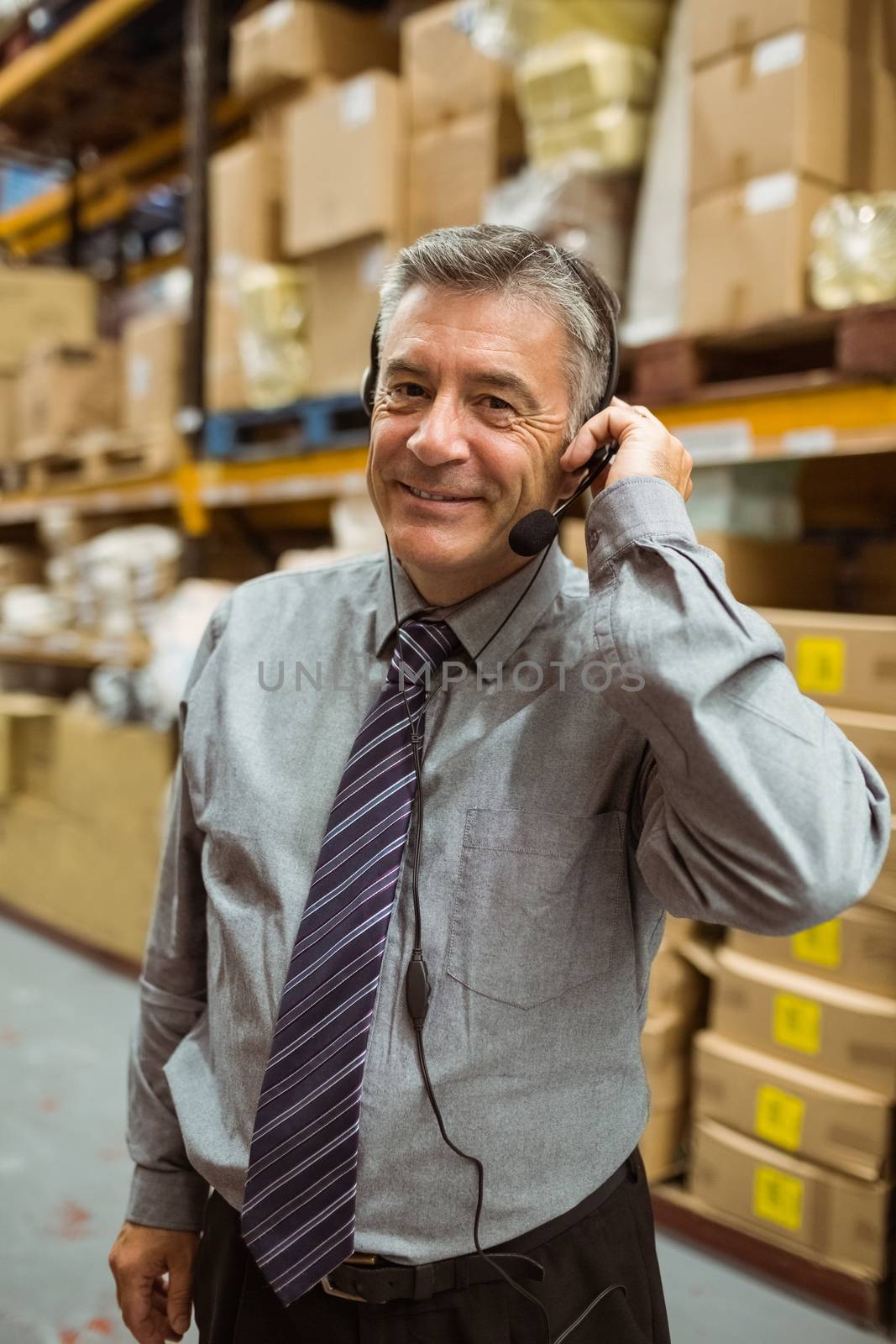 Smiling manager talking in a headset in a large warehouse