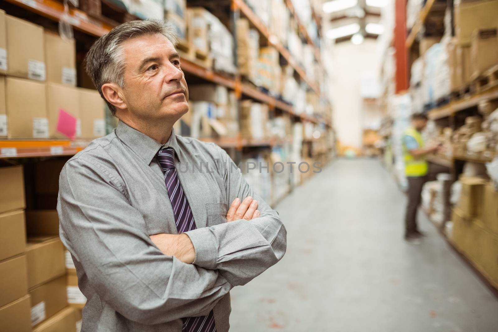 Thoughtful businessman with crossed arms in a large warehouse