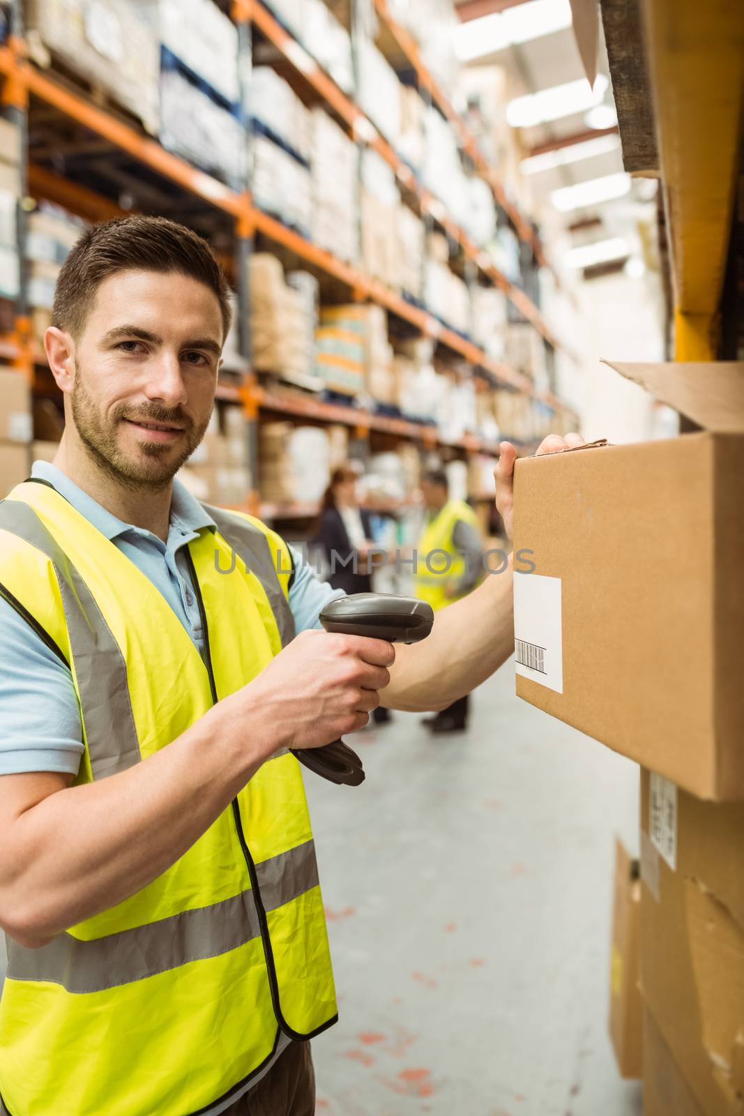 Warehouse worker scanning box while smiling at camera by Wavebreakmedia