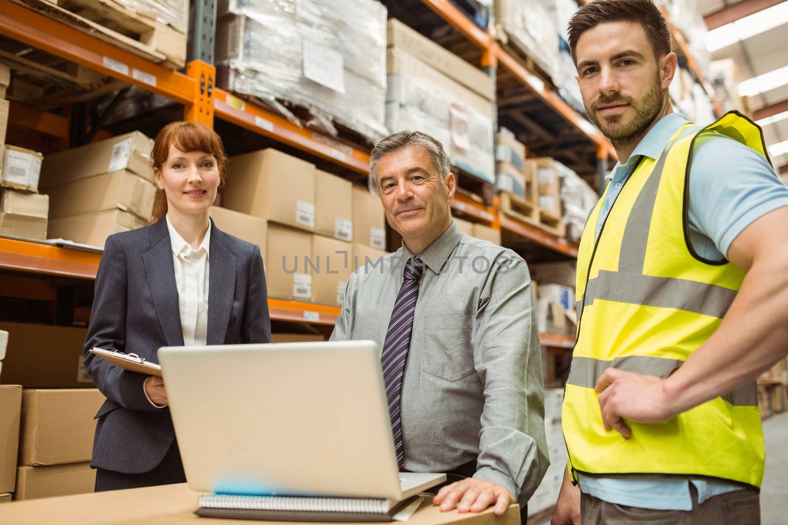 Smiling warehouse team looking at camera in a large warehouse