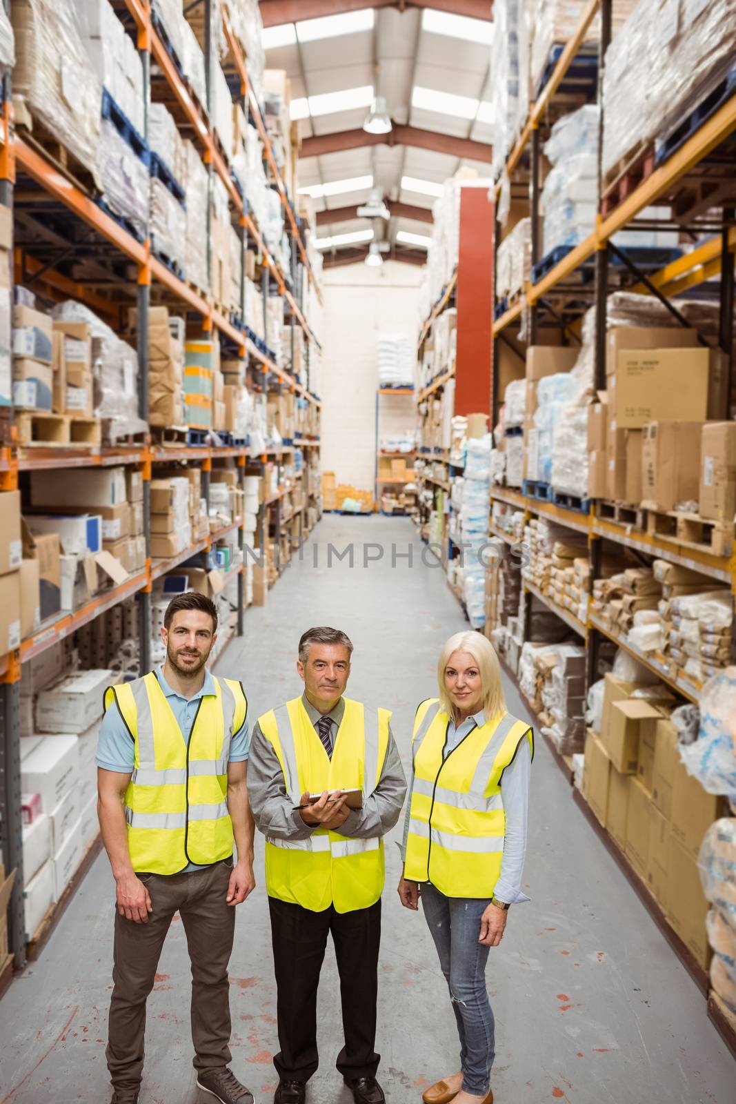 Warehouse team smiling at camera in a large warehouse