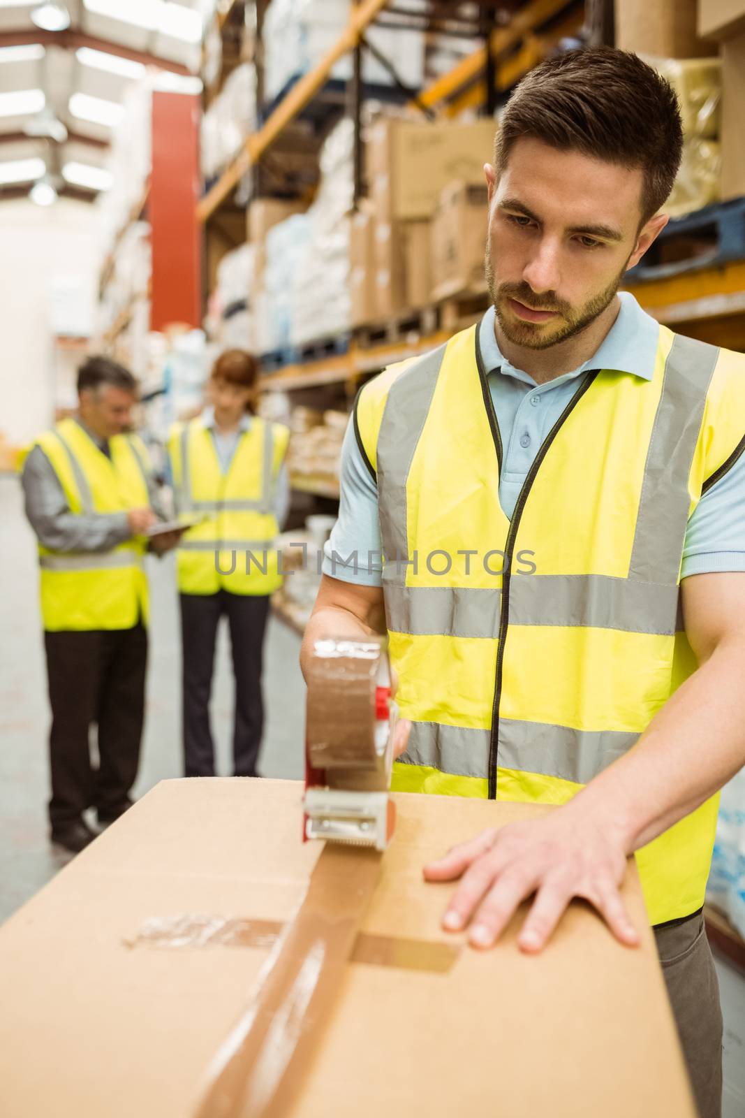 Warehouse worker sealing cardboard boxes for shipping by Wavebreakmedia