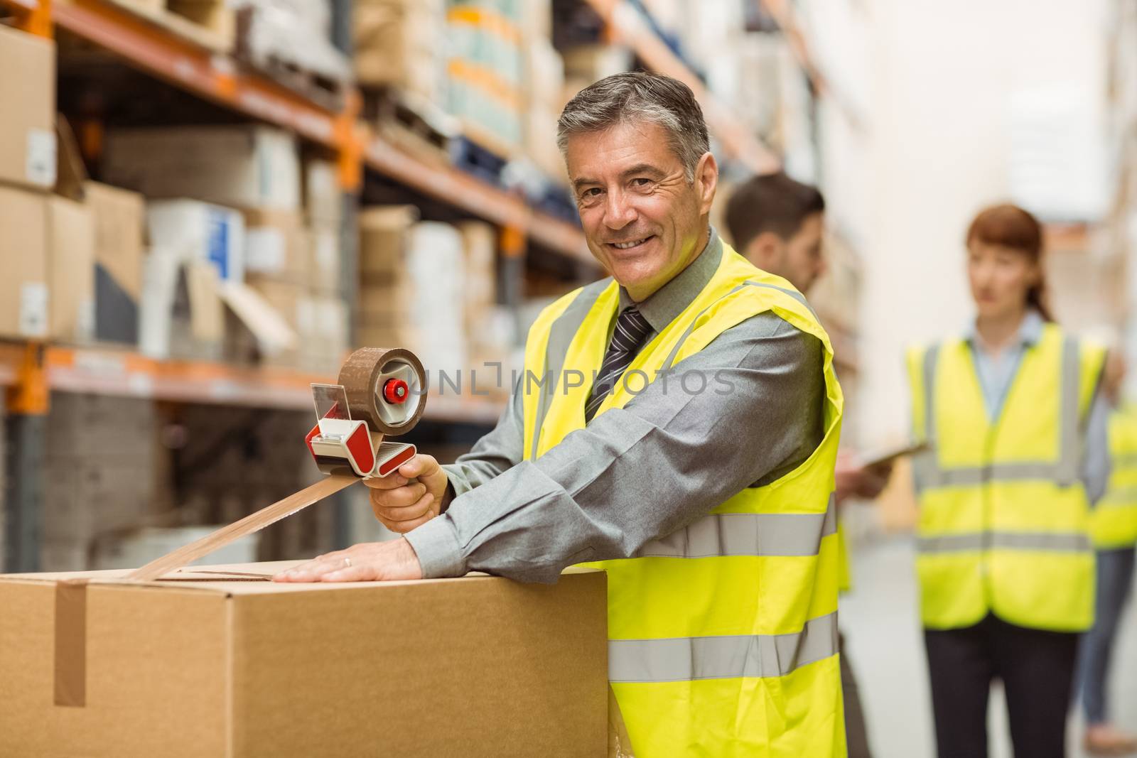 Warehouse worker sealing cardboard boxes for shipping by Wavebreakmedia