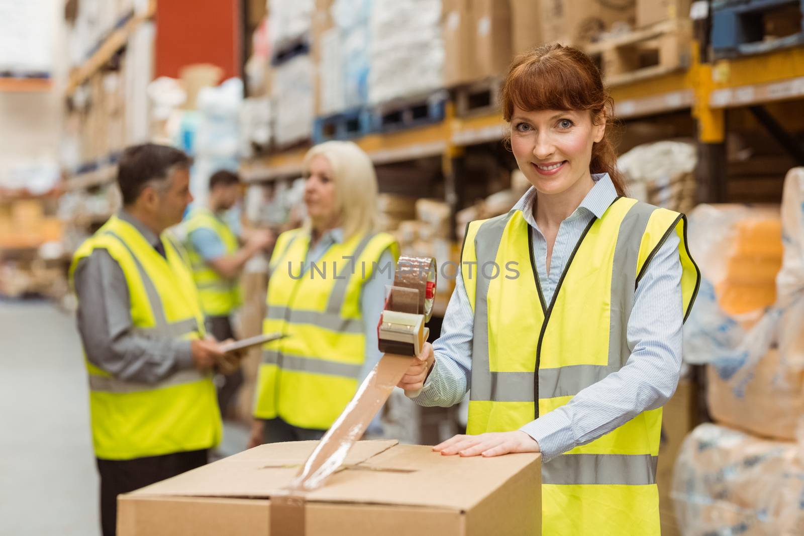 Smiling warehouse workers preparing a shipment in a large warehouse