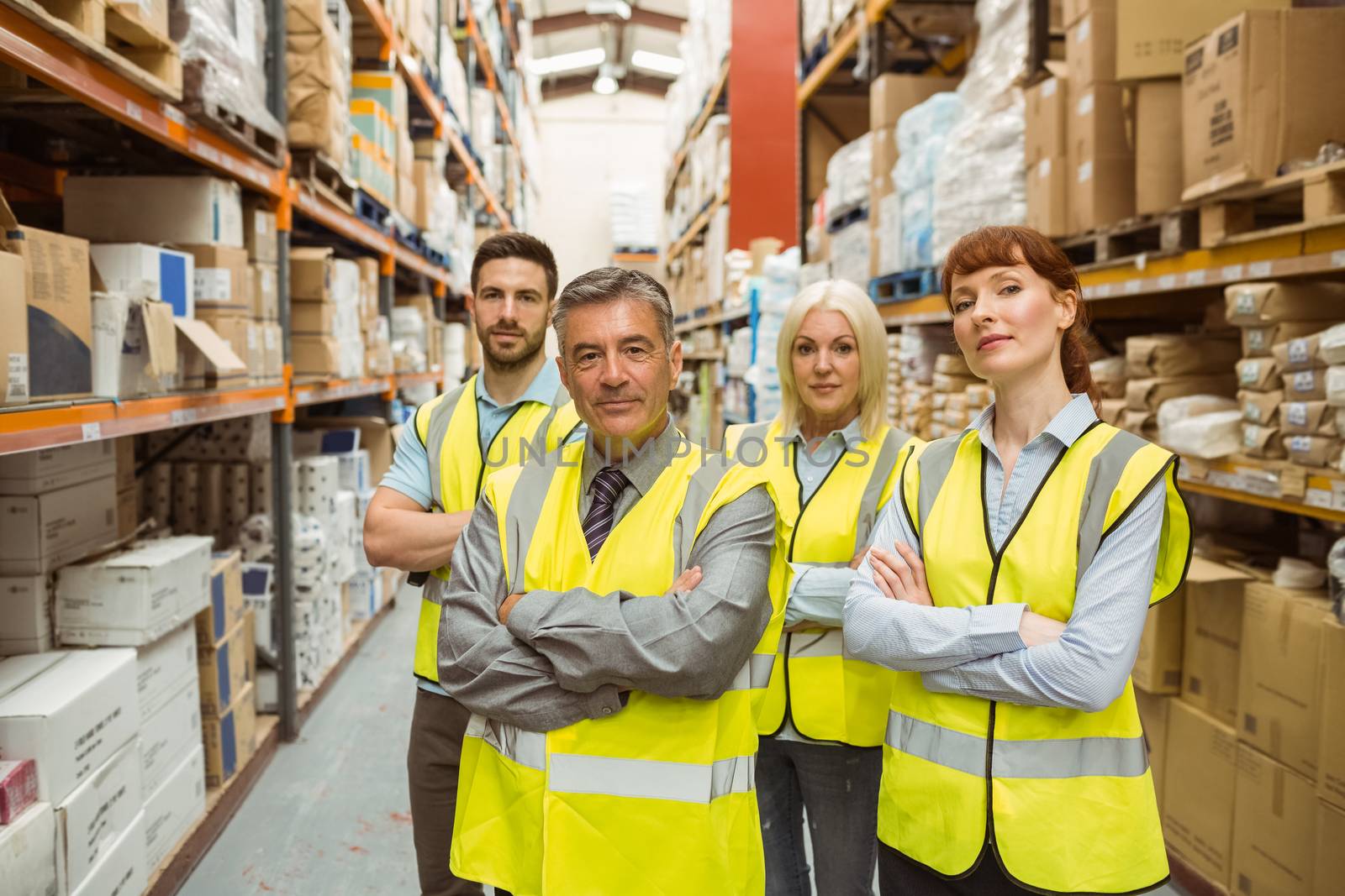 Warehouse team with arms crossed in a large warehouse