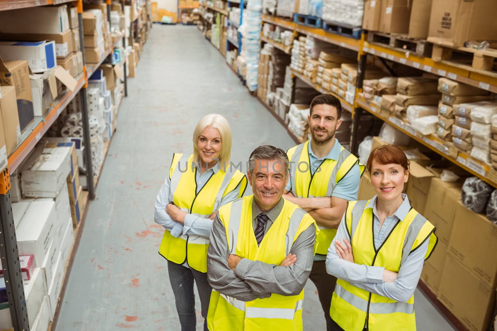 Smiling warehouse team with arms crossed in a large warehouse