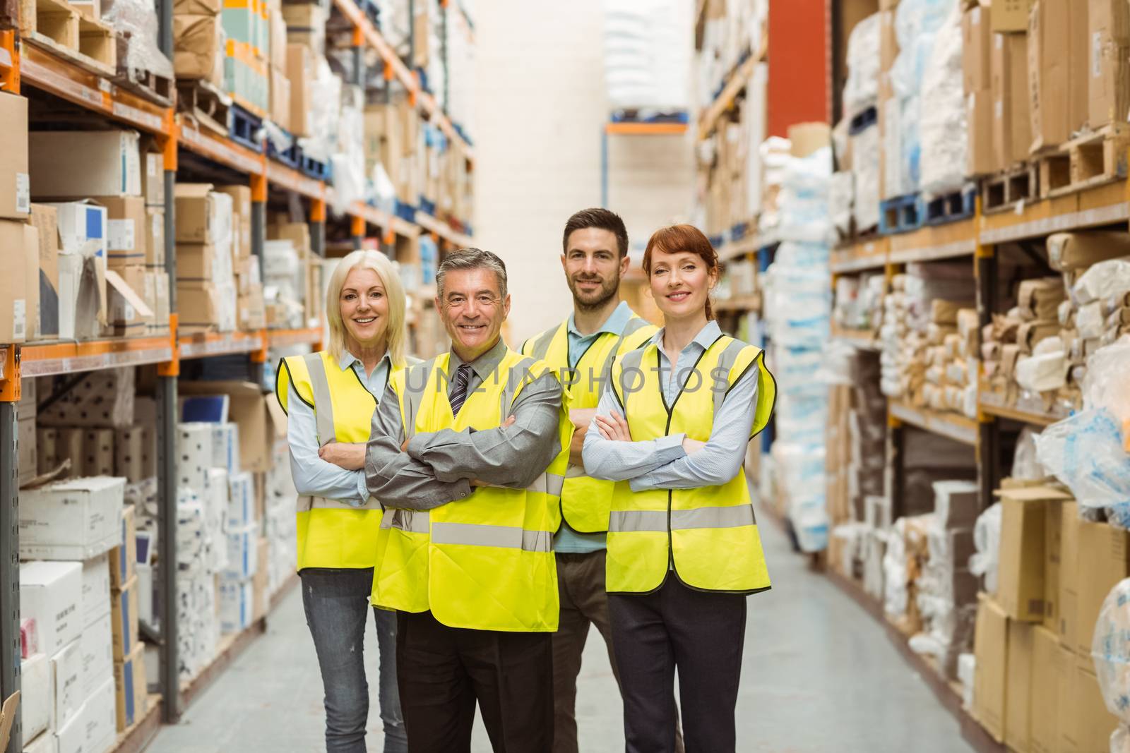 Smiling warehouse team with arms crossed in a large warehouse