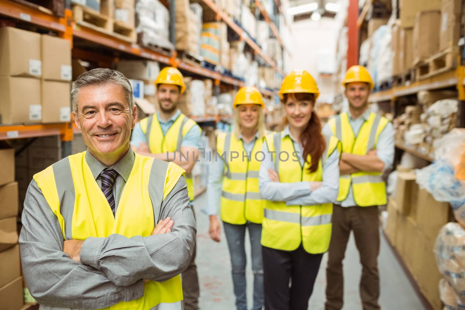 Smiling warehouse team with arms crossed in a large warehouse