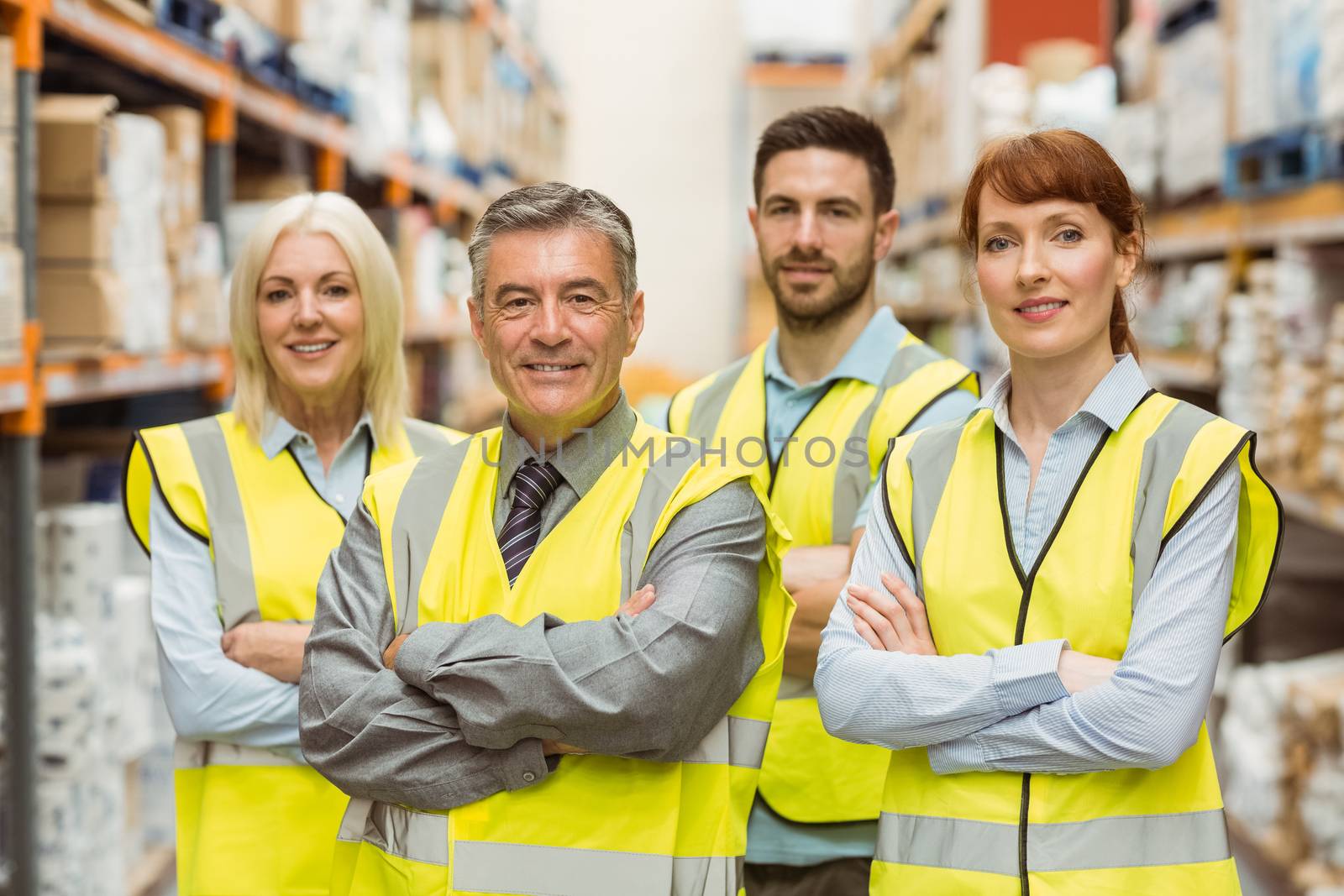 Smiling warehouse team with arms crossed in a large warehouse