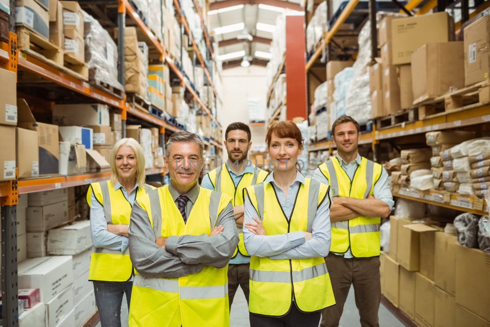 Smiling warehouse team with arms crossed by Wavebreakmedia