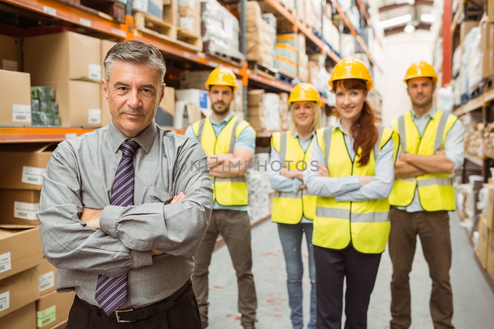 Smiling warehouse team with arms crossed in a large warehouse