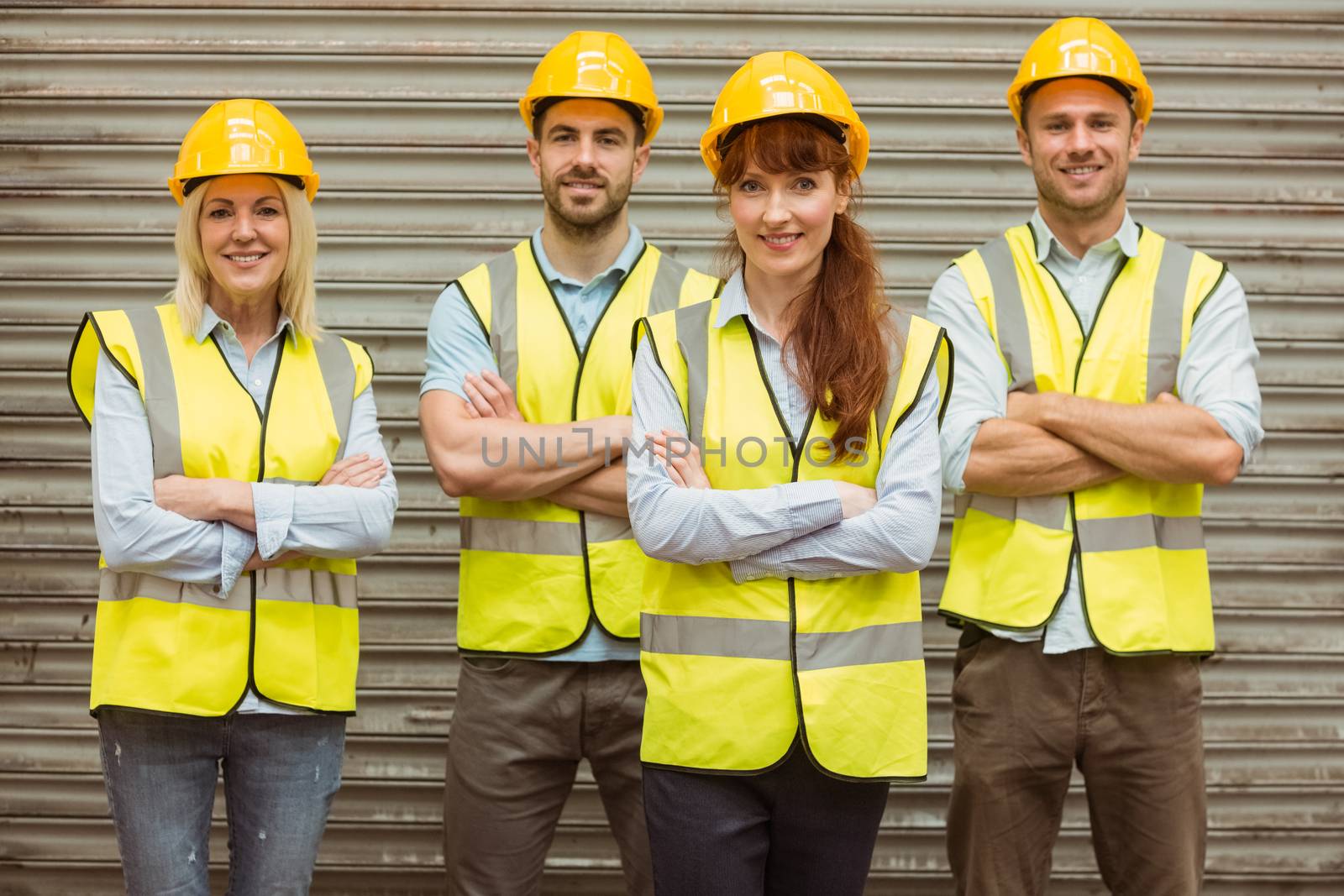 Warehouse team with arms crossed wearing hard hat  by Wavebreakmedia