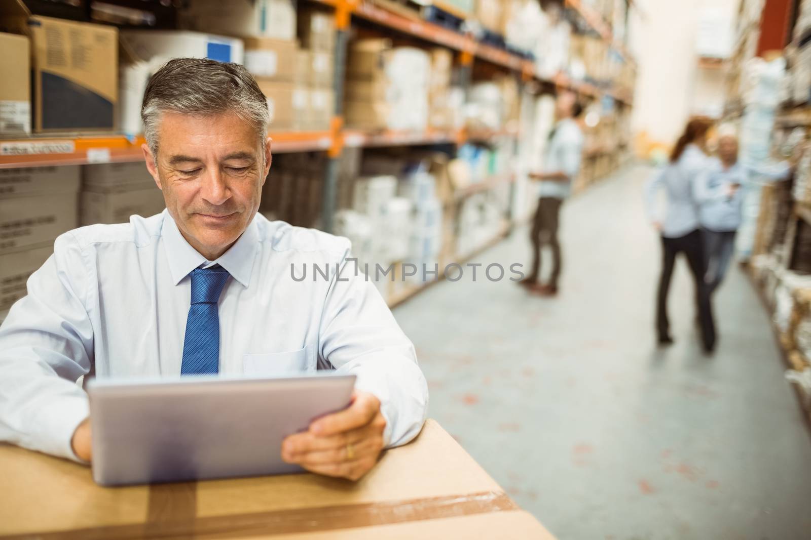 Warehouse manager working on tablet pc in a large warehouse