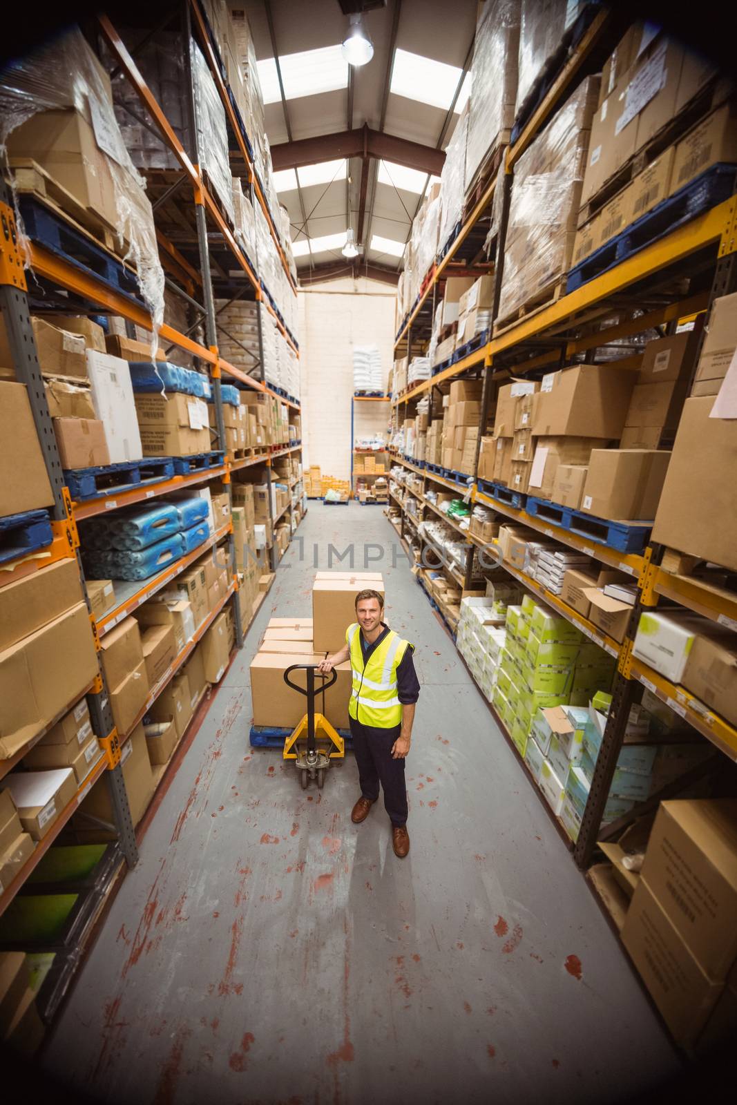 Worker with trolley of boxes in a large warehouse