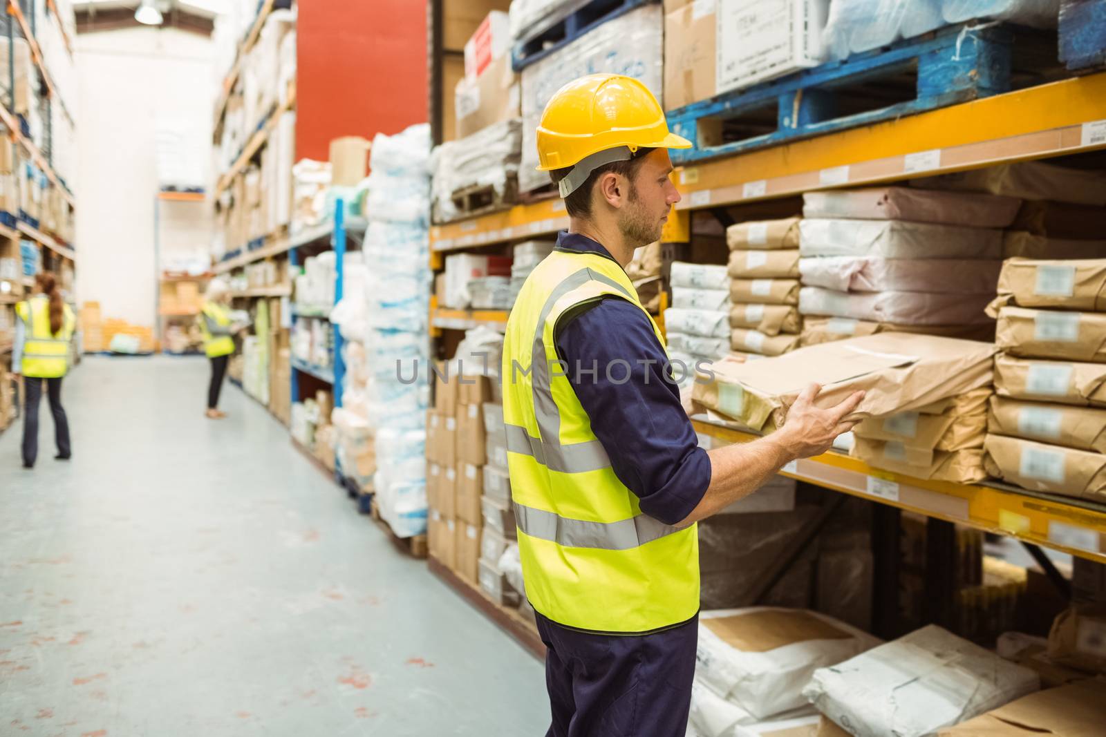 Warehouse worker taking package in the shelf in a large warehouse