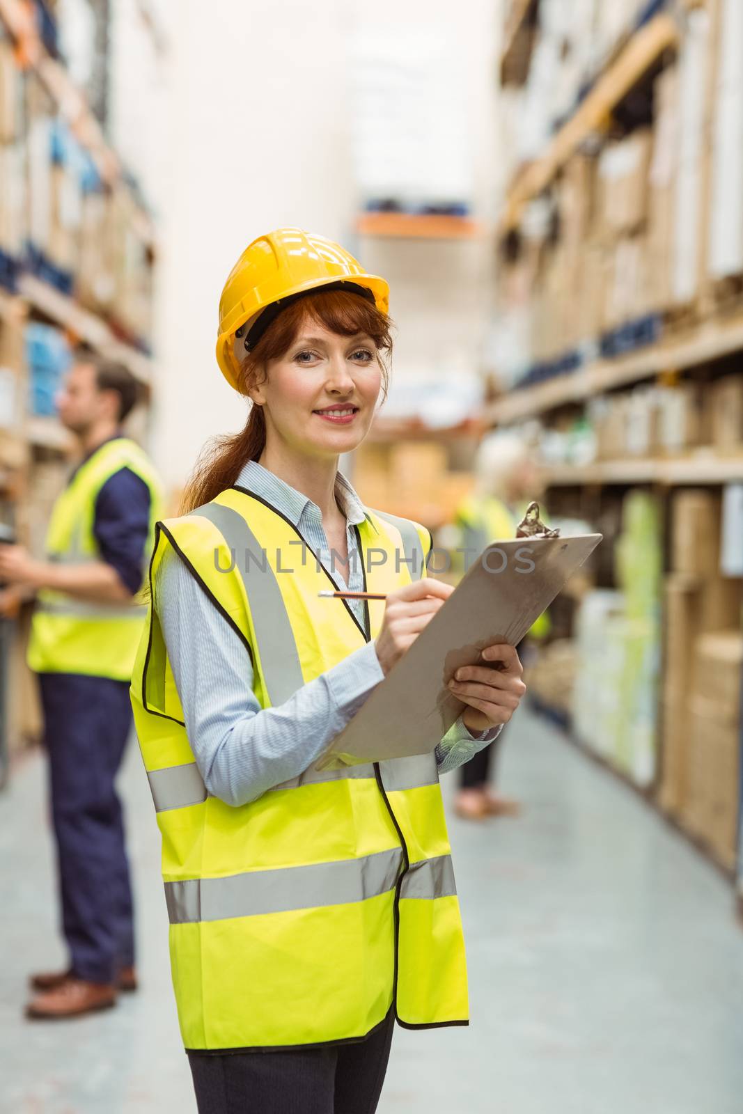 Smiling warehouse manager holding clipboard by Wavebreakmedia