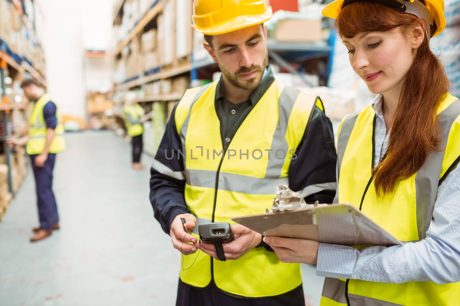 Warehouse team working together with clipboard in a large warehouse