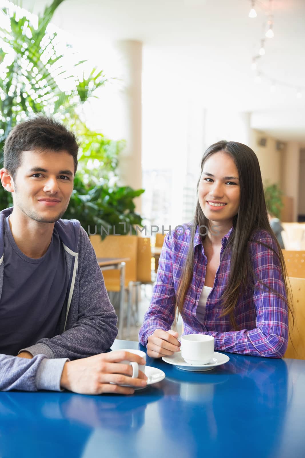 Young students smiling at camera in cafe by Wavebreakmedia