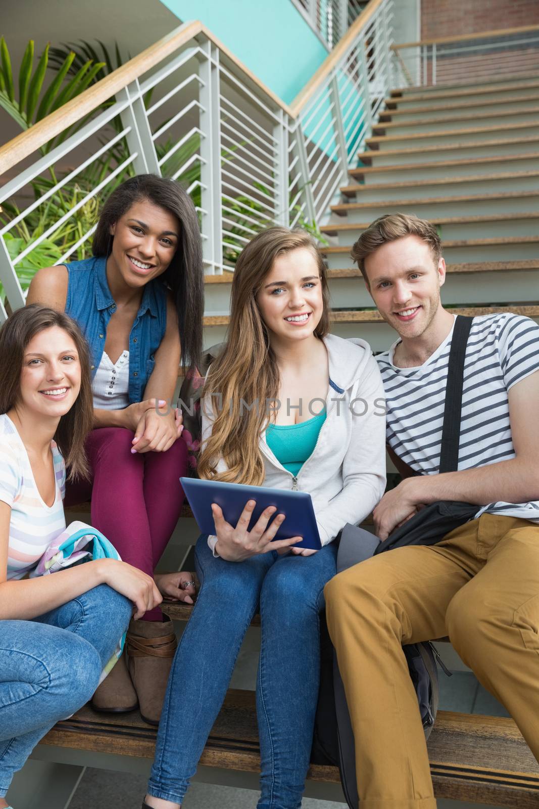 Smiling students sitting on steps with tablet pc by Wavebreakmedia