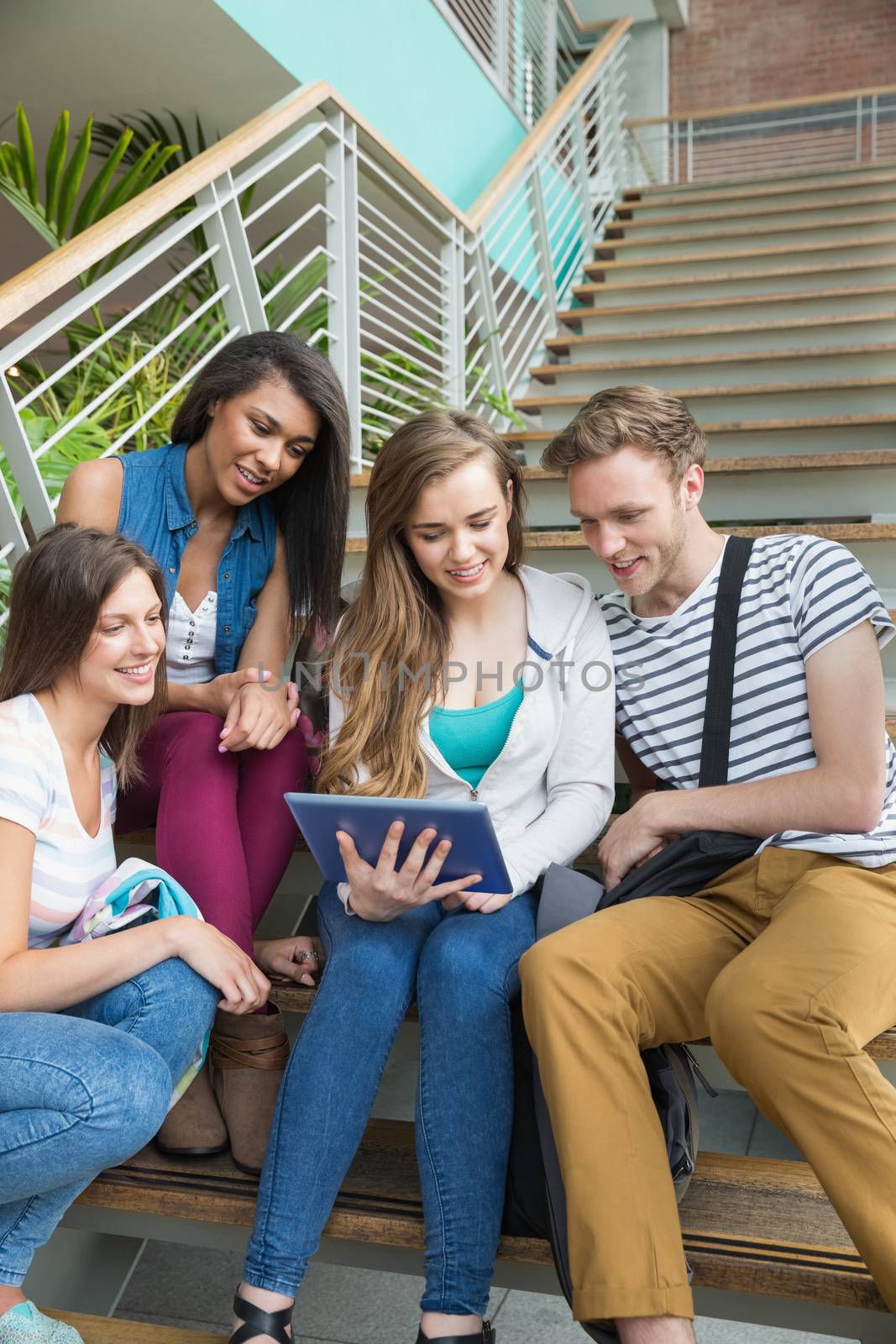Smiling students sitting on steps with tablet pc by Wavebreakmedia