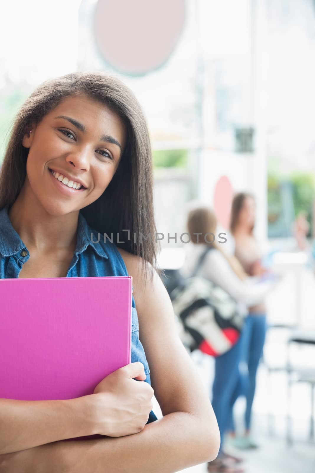 Pretty student smiling and holding notepads by Wavebreakmedia