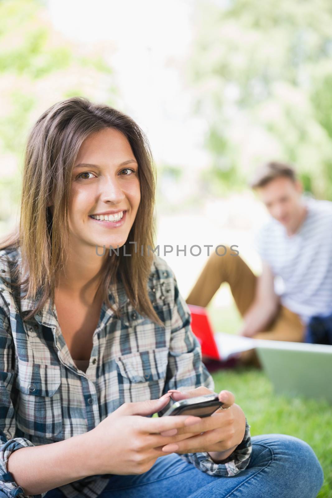 Happy students sitting outside on campus  by Wavebreakmedia