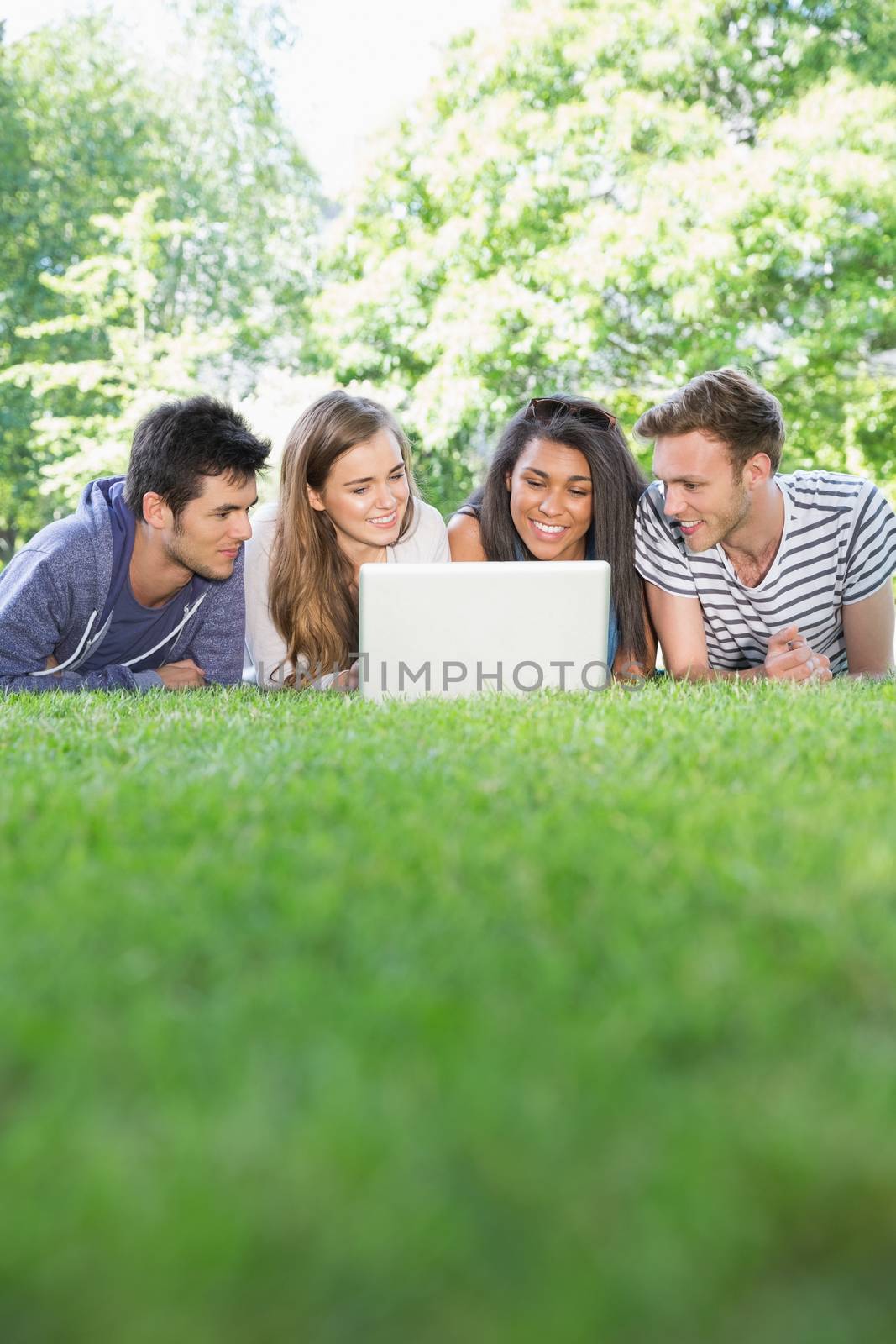 Happy students using laptop outside at the university