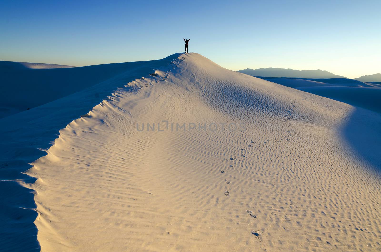 Hiker On Top of a Sand Dune; sunset in the background