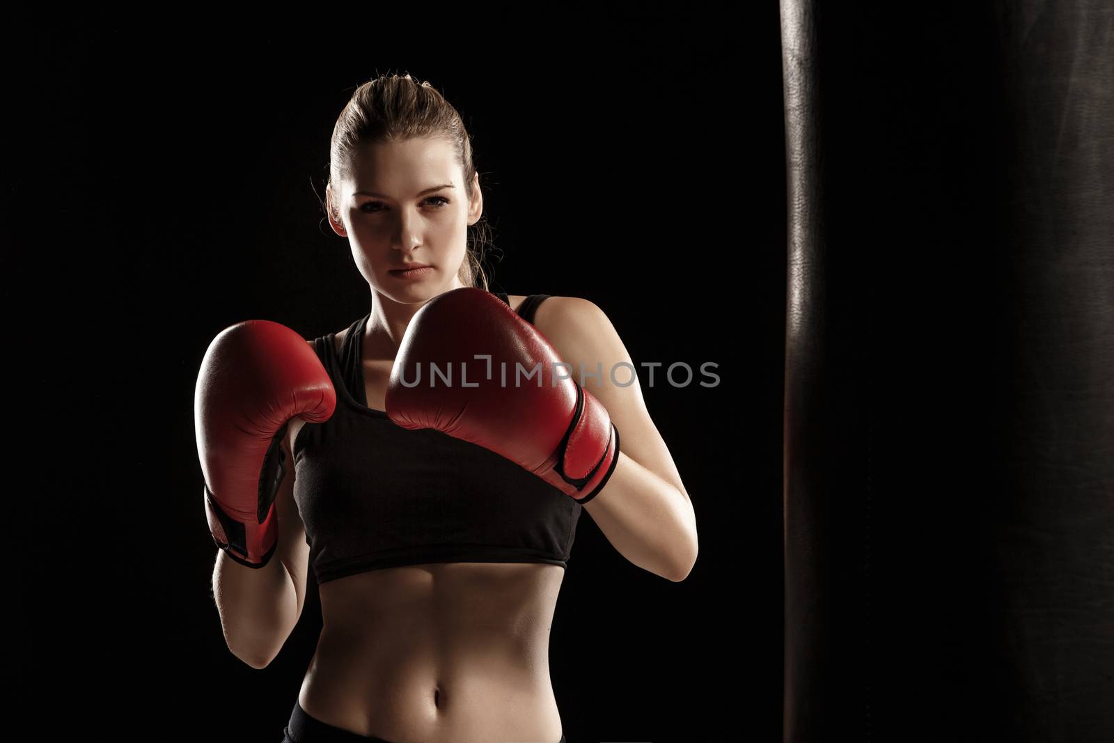 beautiful woman with the red gloves is boxing on black background