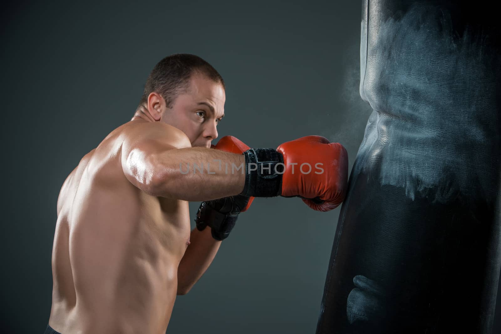 Young boxer in red gloves fighter over black background