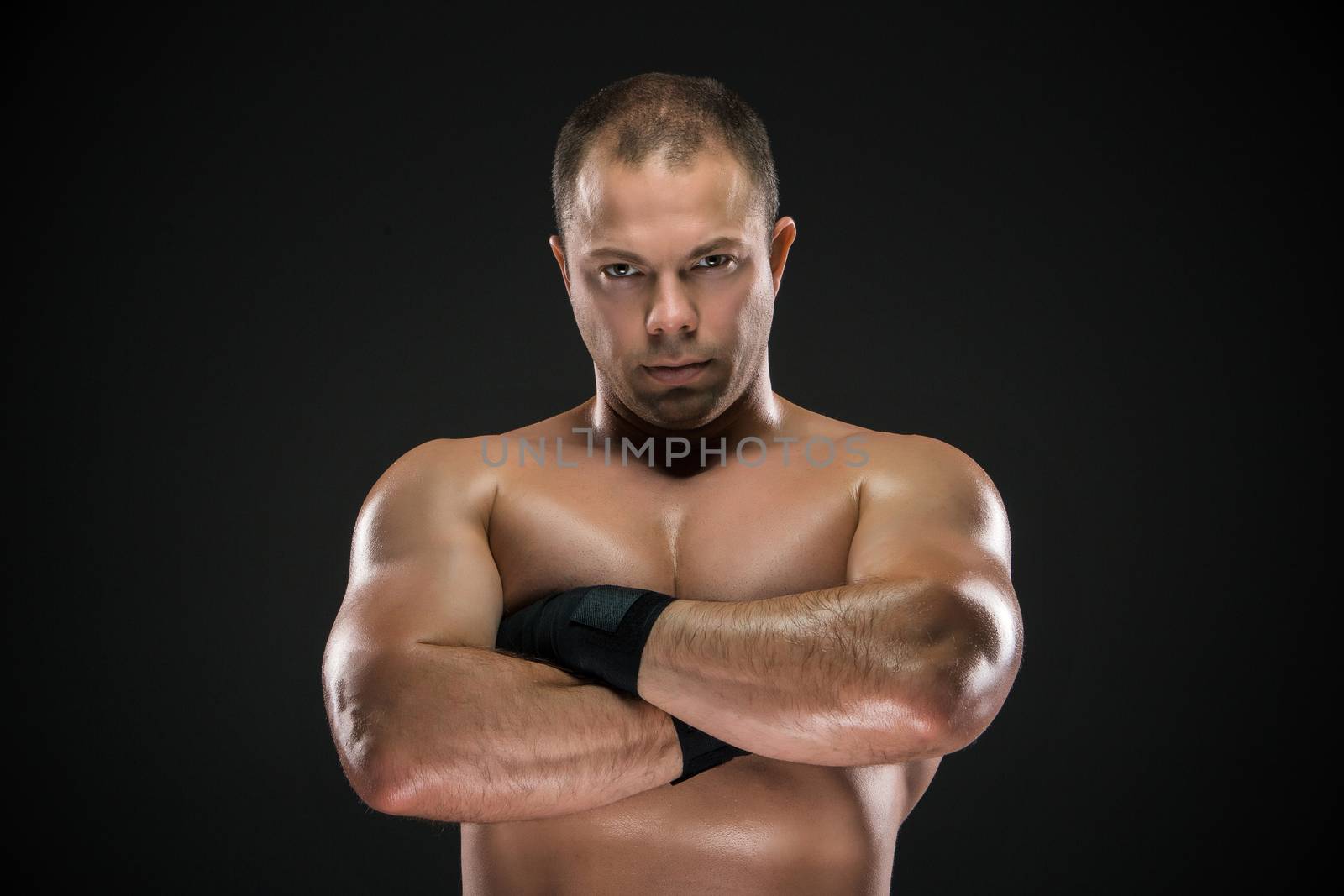 studio portrait of young caucasian boxer with folded hands posing over dark background