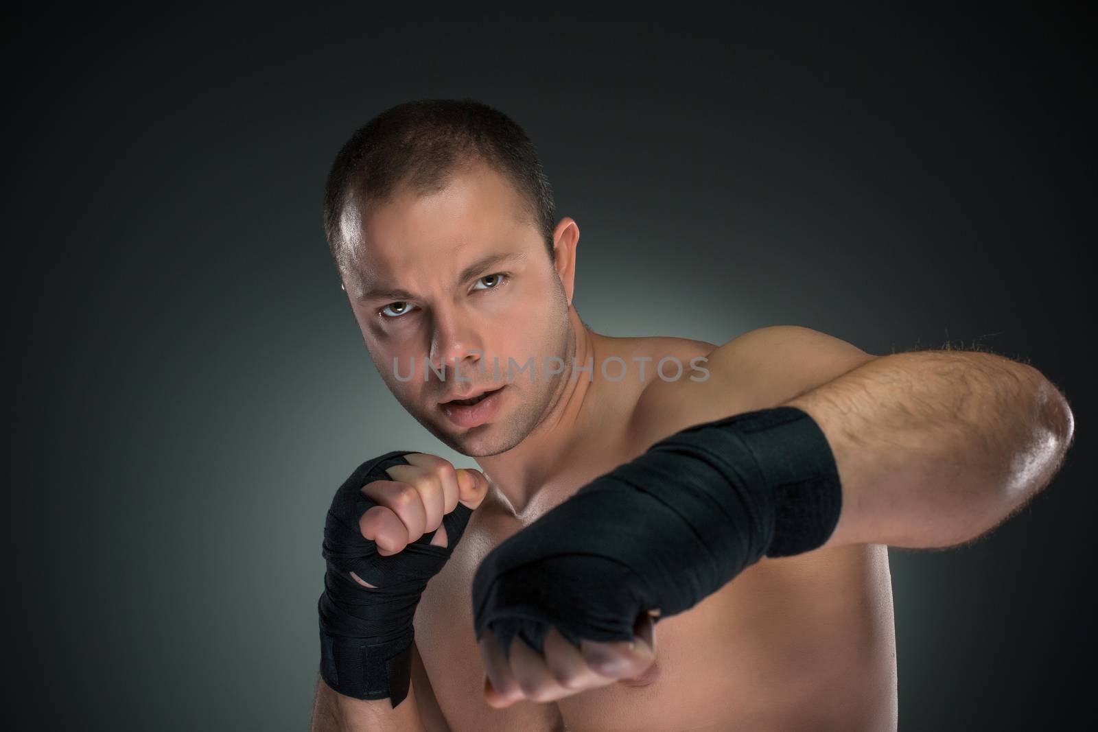 Young boxer boxing over the black background