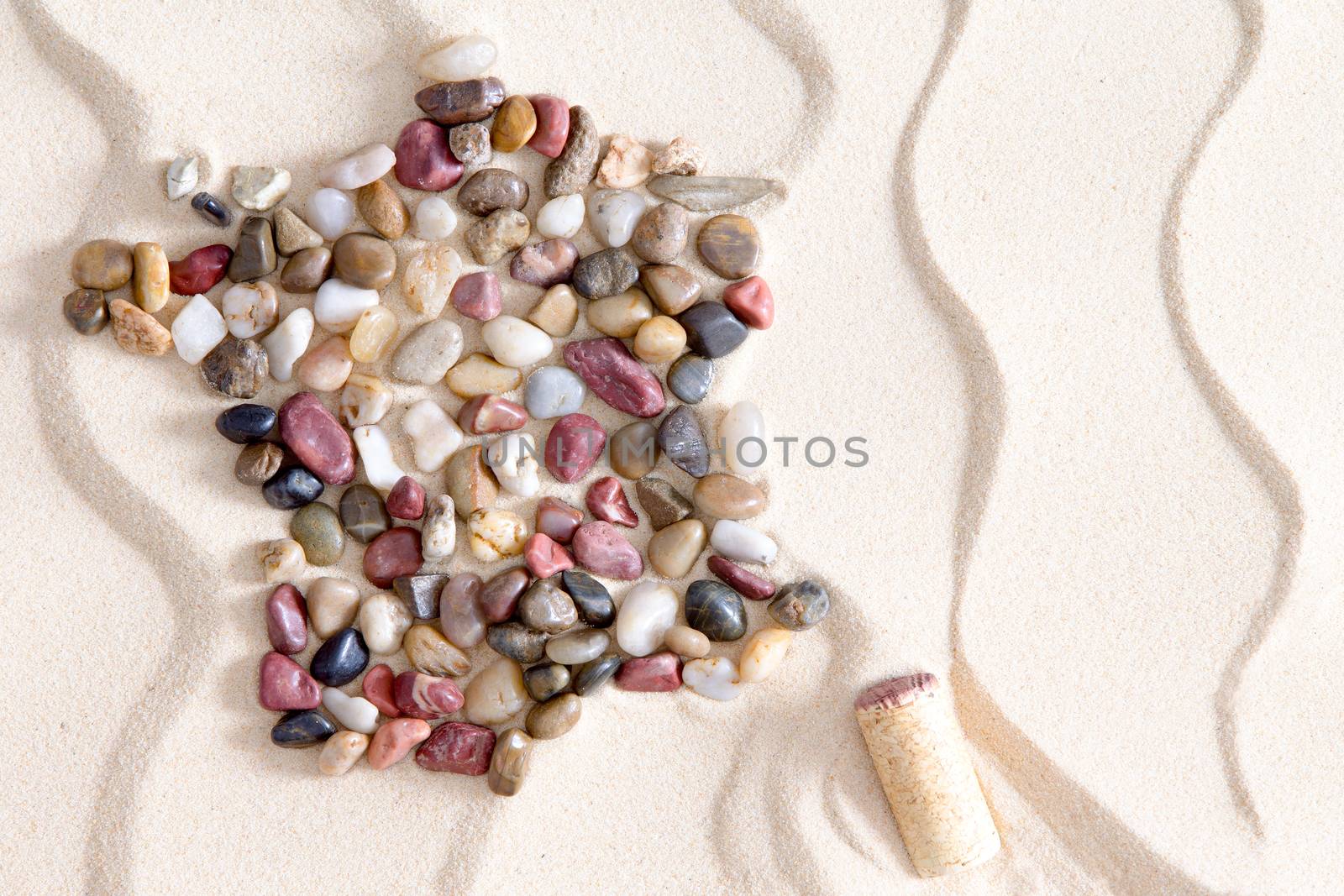 Artistic map of France from colorful waterworn pebbles arranged on decorative white sand with a pattern of wavy lines with Corsica island formed by a wine bottle cork, copy space in a conceptual image