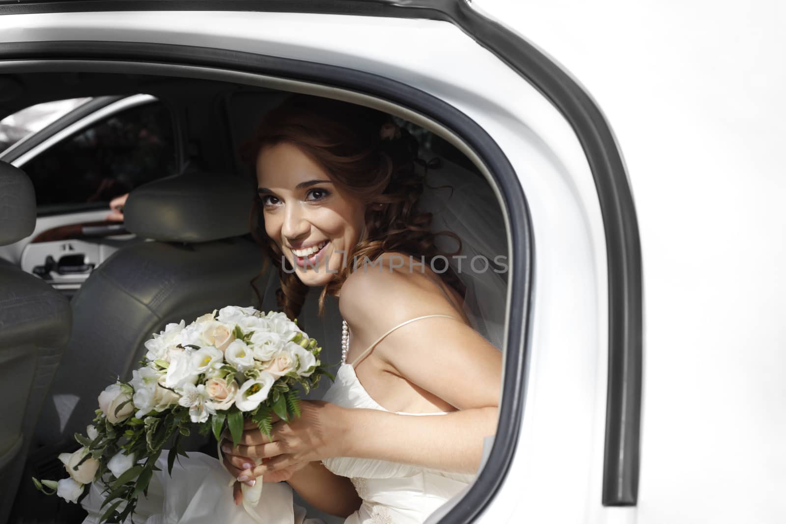 Beautiful bride with wedding bouquet in white car 
