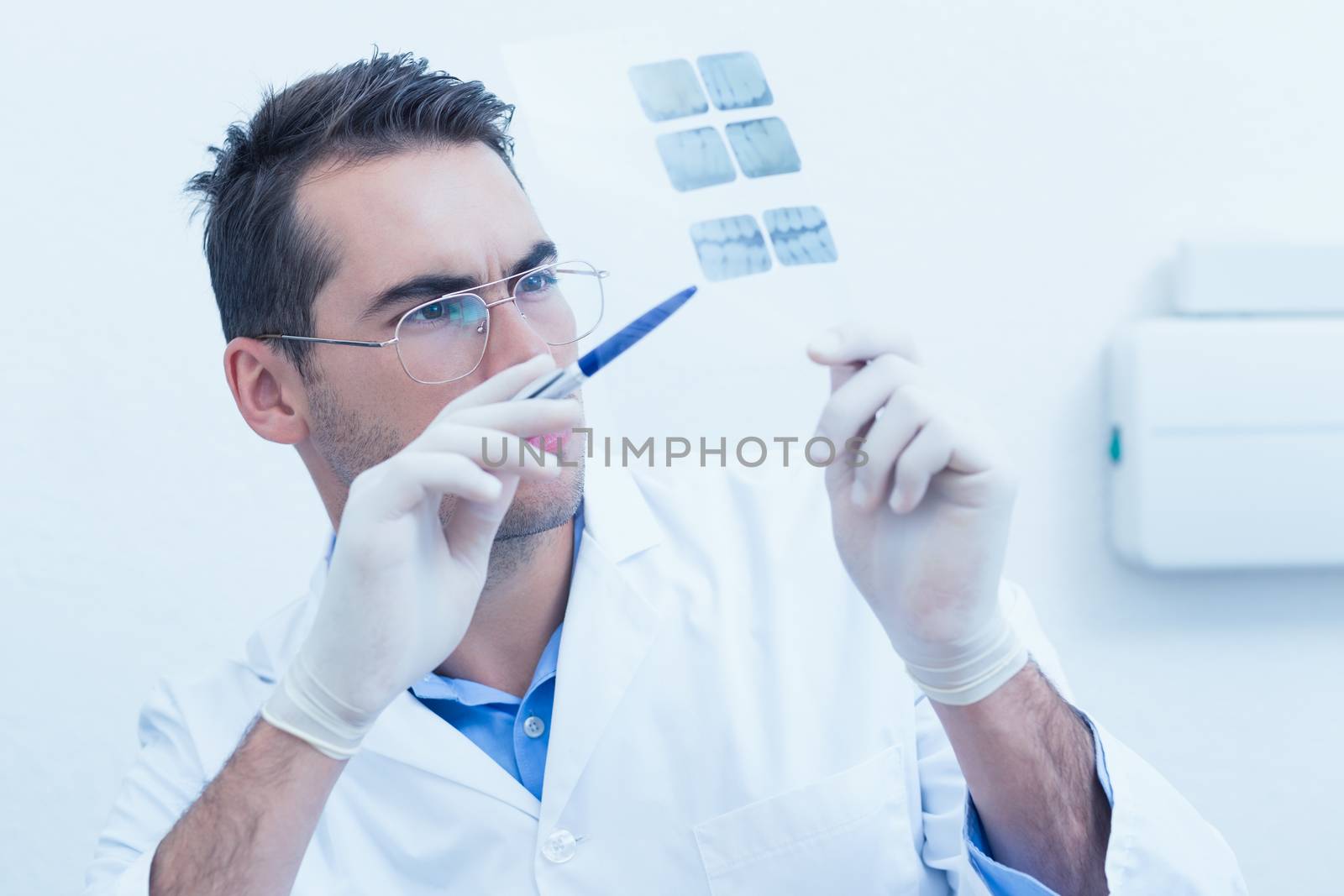 Concentrated male dentist looking at x-ray