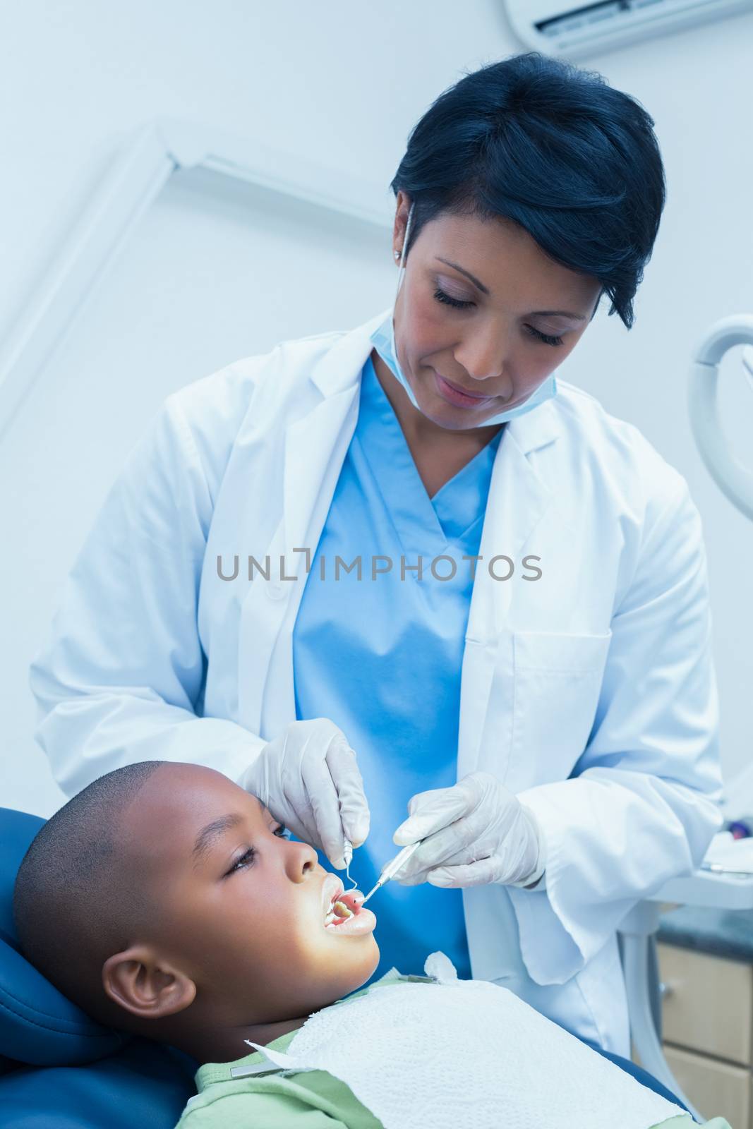 Female dentist examining boys teeth by Wavebreakmedia