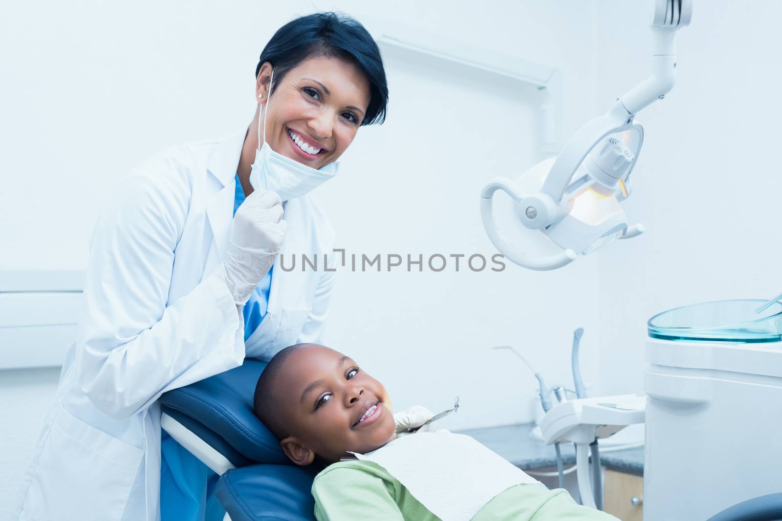 Portrait of smiling female dentist examining boys teeth in the dentists chair
