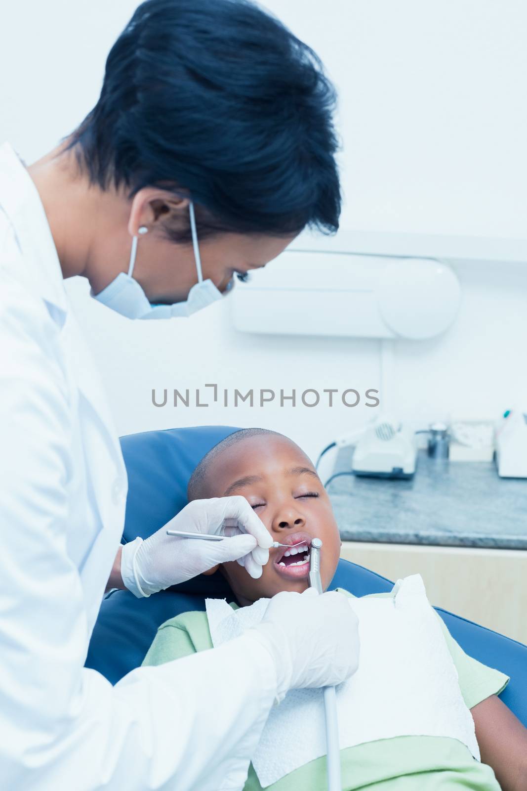 Female dentist examining boys teeth in dentists chair by Wavebreakmedia