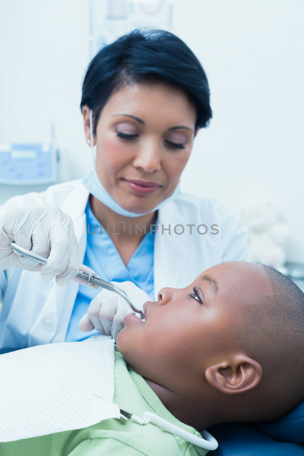 Female dentist examining boys teeth in dentists chair by Wavebreakmedia