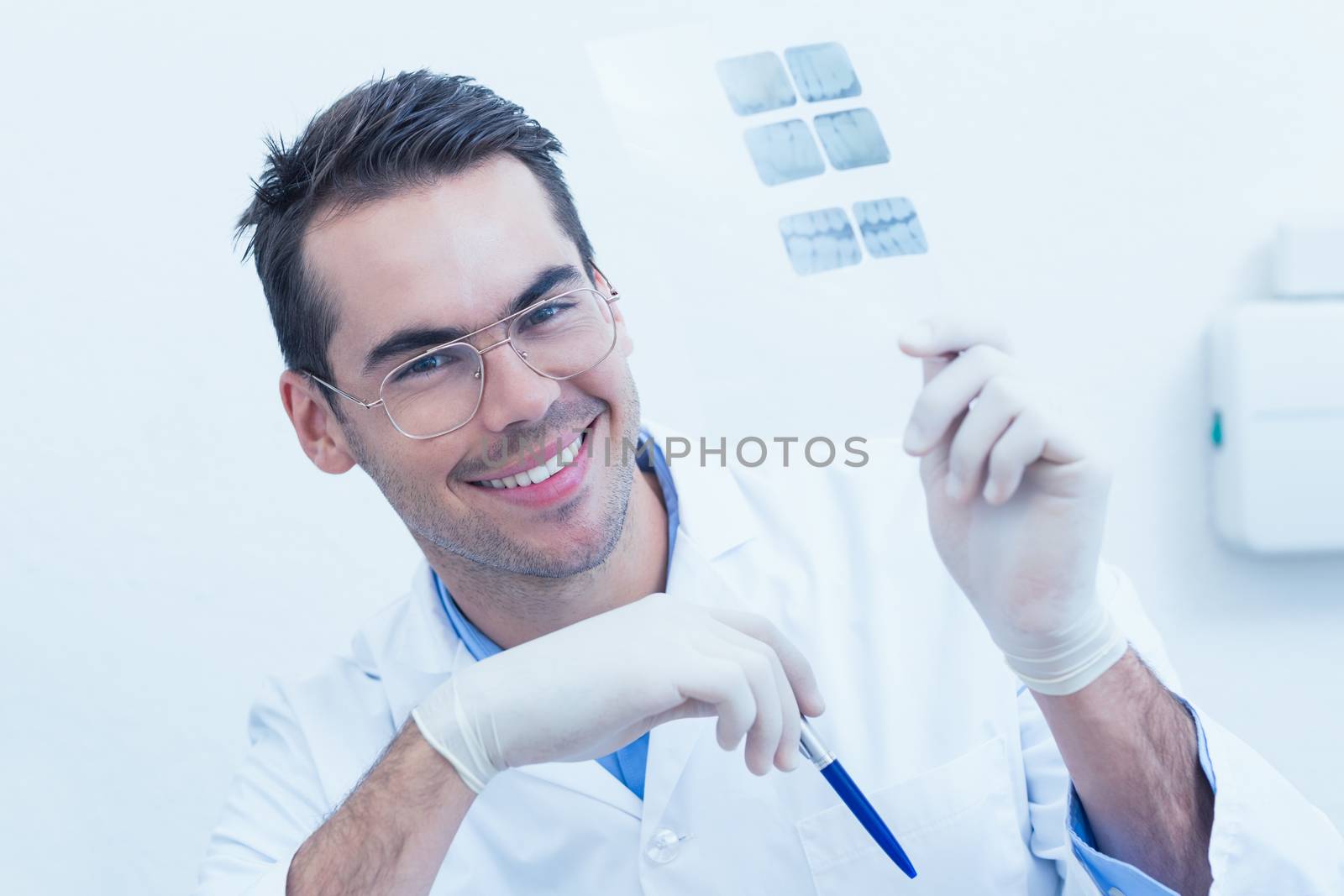 Smiling male dentist holding at x-ray by Wavebreakmedia