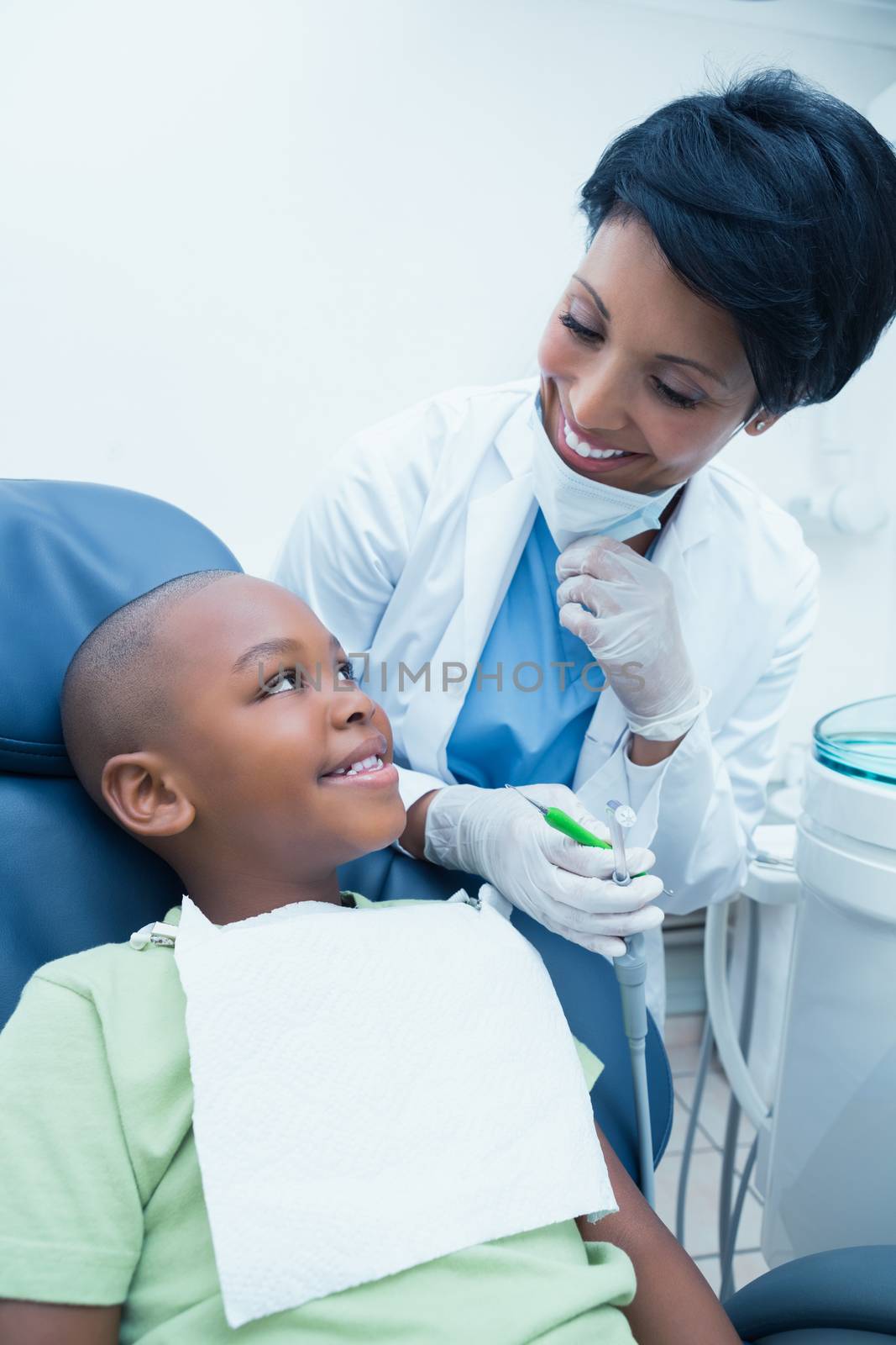 Portrait of smiling female dentist examining boys teeth in the dentists chair