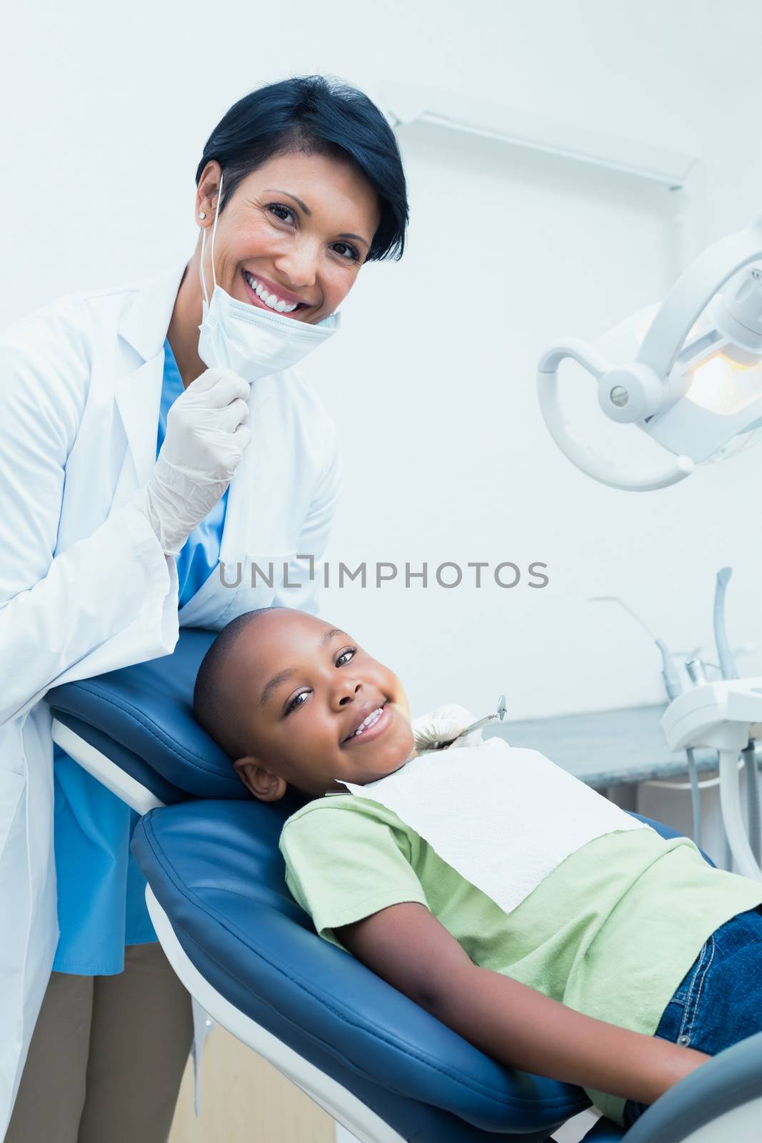 Portrait of smiling female dentist examining boys teeth in the dentists chair