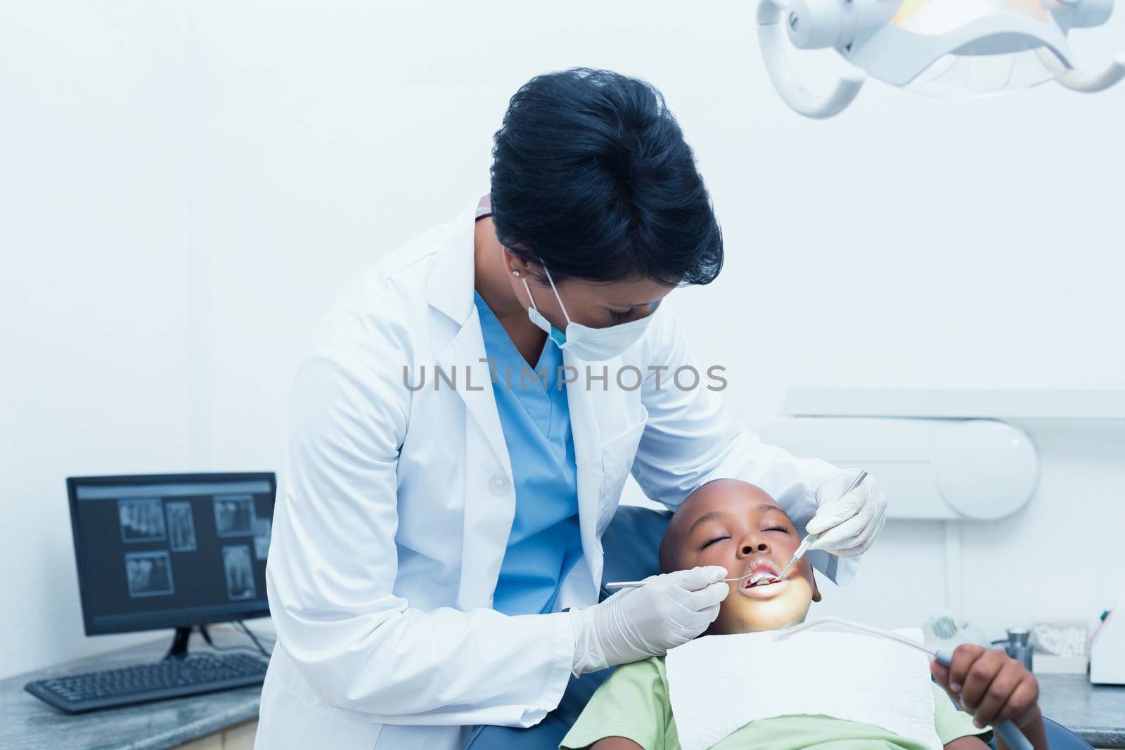 Female dentist examining boys teeth in the dentists chair