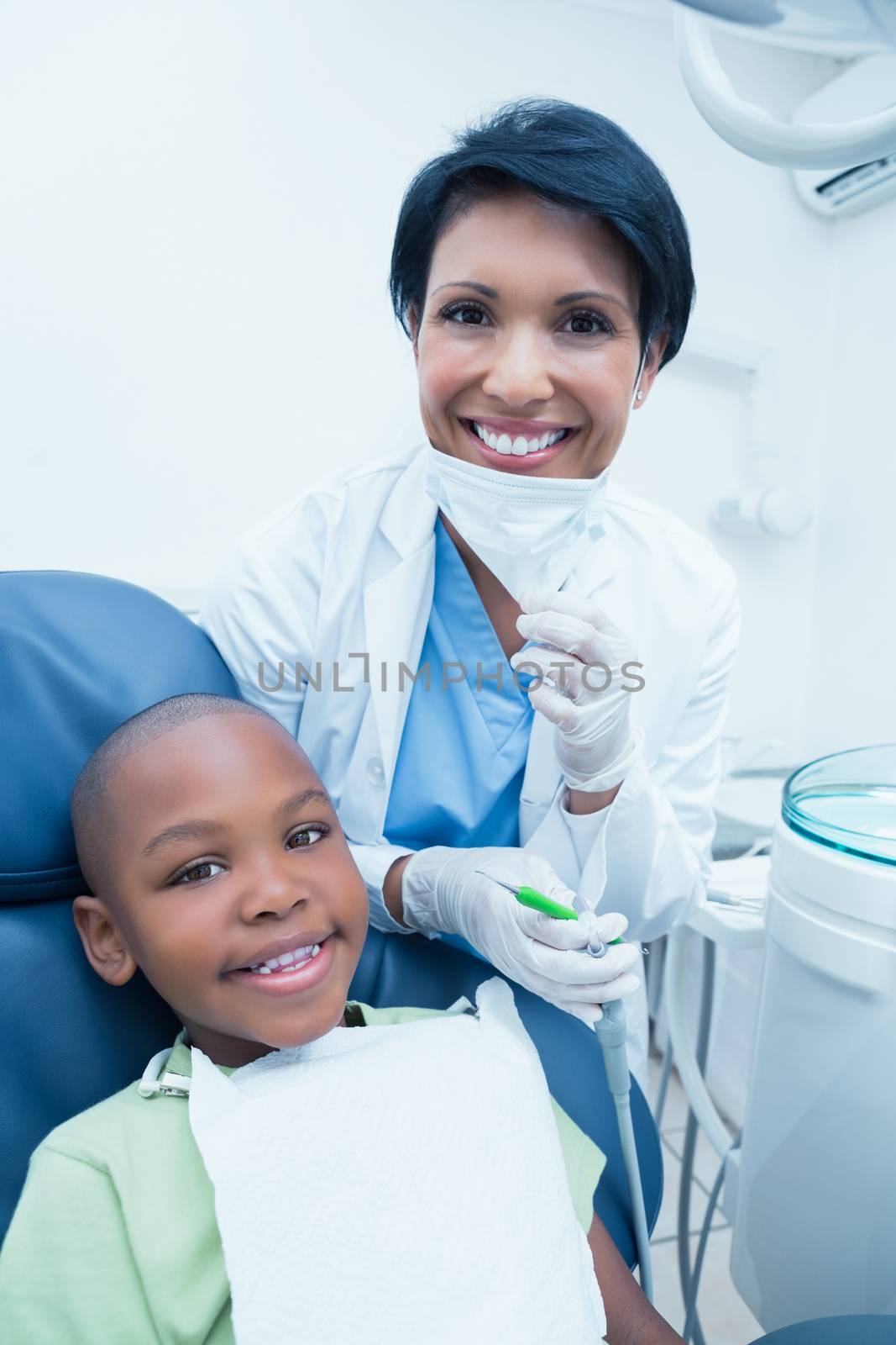 Portrait of smiling female dentist examining boys teeth in the dentists chair